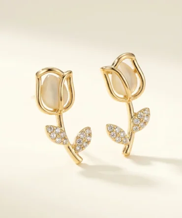 Gold plated tulip dangler earring with mother of pearl bud and CZ pavé leaf stem worn on ear, lifestyle close-up