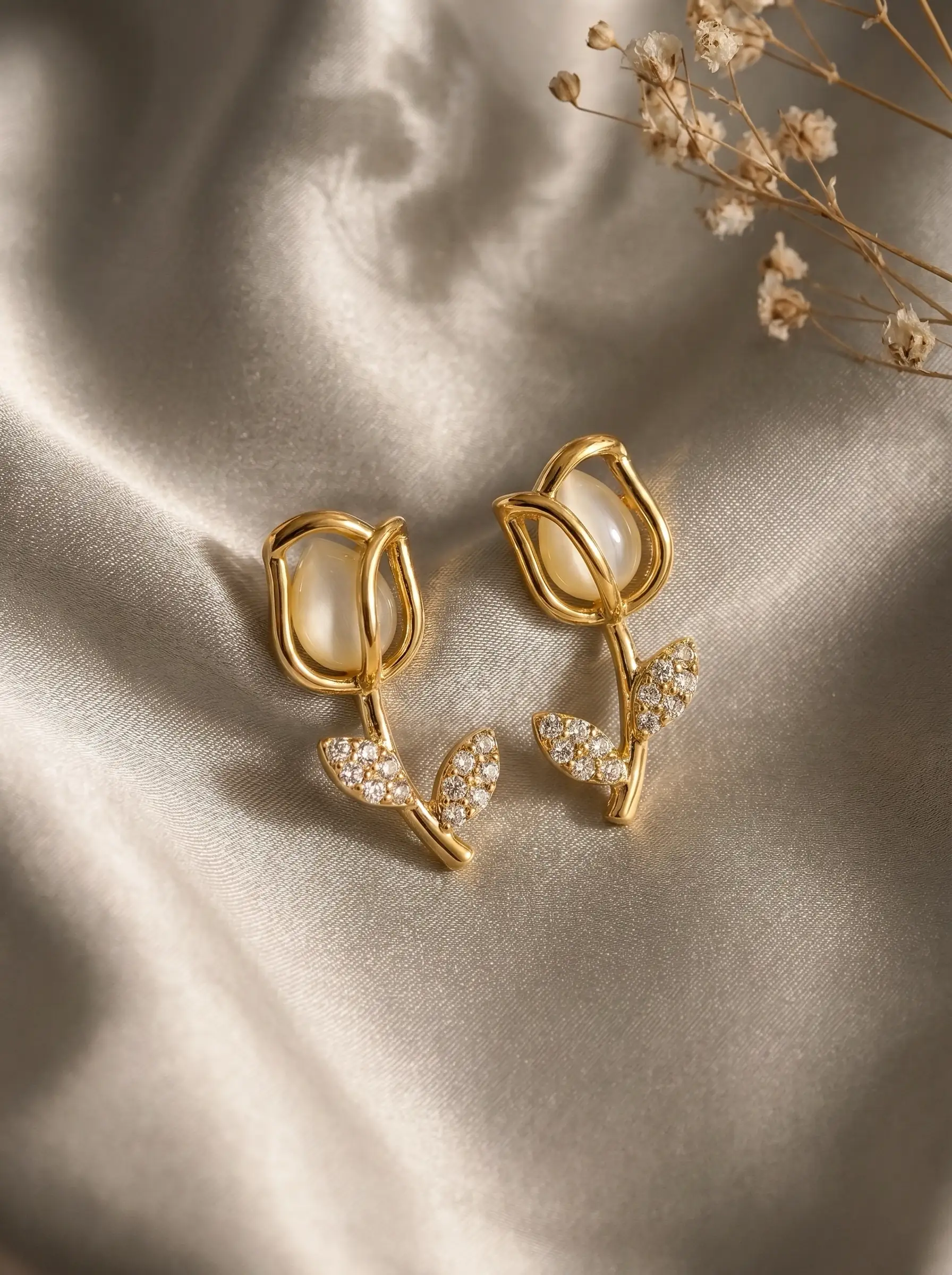 Gold plated tulip dangler earring with mother of pearl bud and CZ pavé leaf stem worn on ear, lifestyle close-up