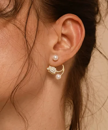 Gold plated open-back earrings with large pearl, CZ tulip charm and small pearl tip on silk fabric flatlay