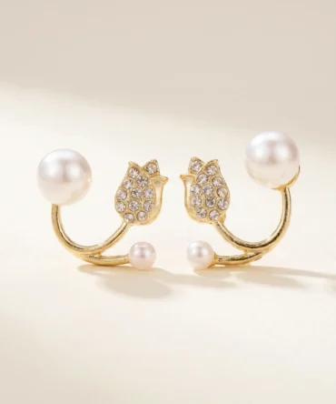 Gold plated open-back earrings with large pearl, CZ tulip charm and small pearl tip on silk fabric flatlay