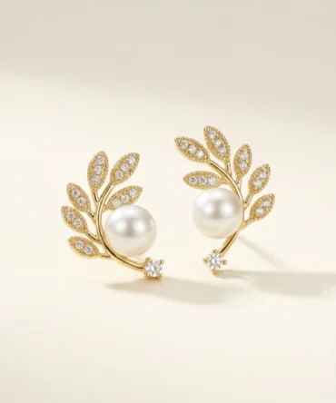 Gold plated olive branch stud earrings with CZ pavé leaves, centred pearl and solitaire CZ tip, studio product pair shot