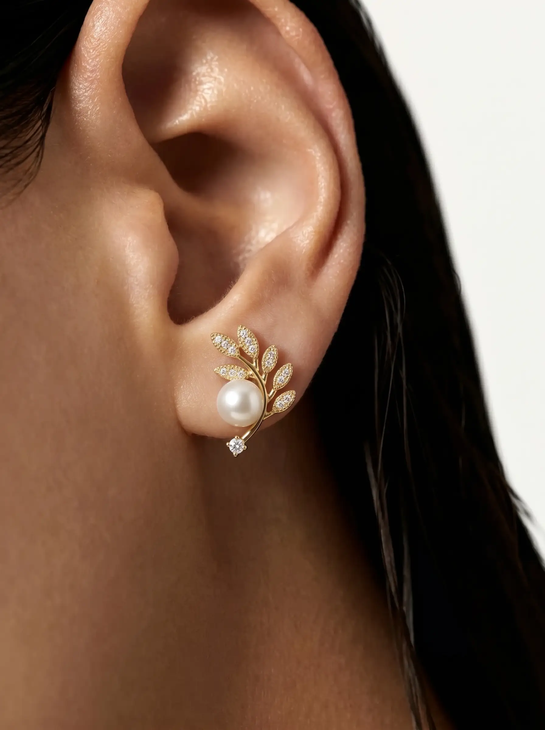 Gold plated olive branch stud earrings with CZ pavé leaves, centred pearl and solitaire CZ tip, studio product pair shot