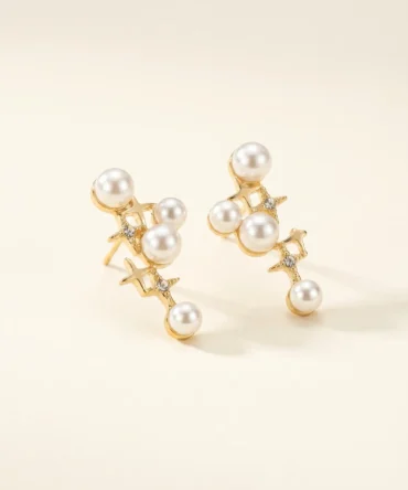 Gold plated cascading pearl drop earrings with four-pointed star CZ connectors, five pearl cluster design, studio product pair shot