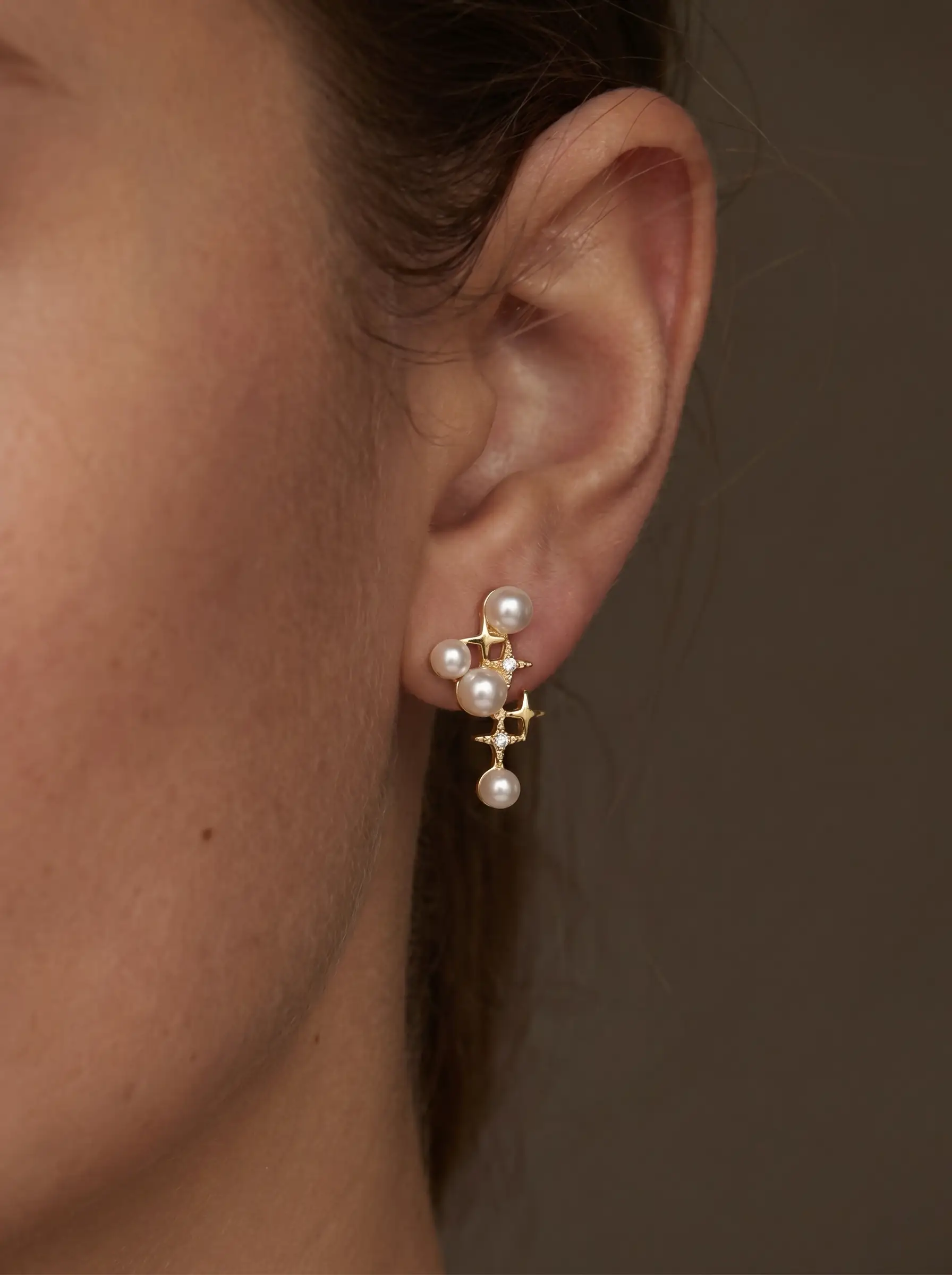 Gold plated cascading pearl drop earrings with four-pointed star CZ connectors, five pearl cluster design, studio product pair shot