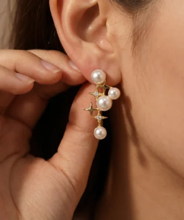 Gold plated cascading pearl drop earrings with four-pointed star CZ connectors, five pearl cluster design, studio product pair shot