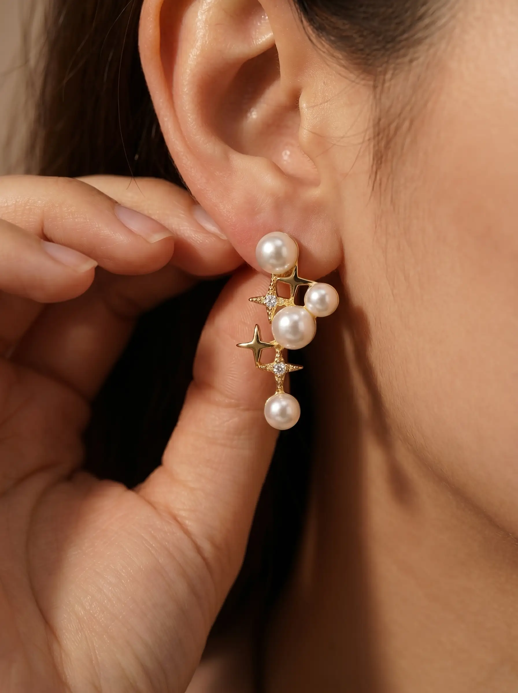 Gold plated cascading pearl drop earrings with four-pointed star CZ connectors, five pearl cluster design, studio product pair shot