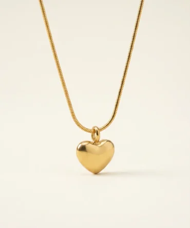 Gold plated puffy heart pendant on snake chain necklace, studio shot on neutral background