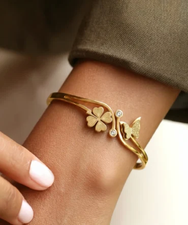 Gold plated bracelet with floral charm and butterfly detail on structured band for women