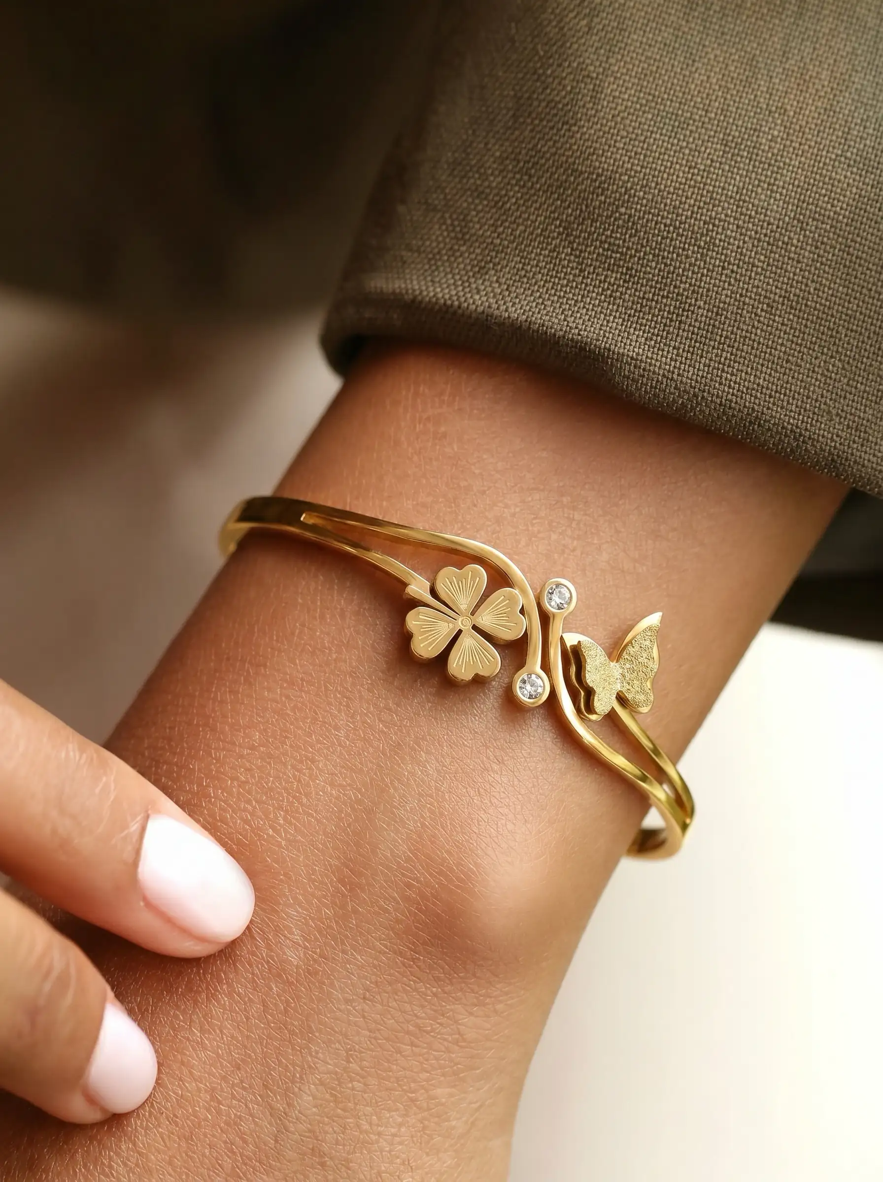 Gold plated bracelet with floral charm and butterfly detail on structured band for women