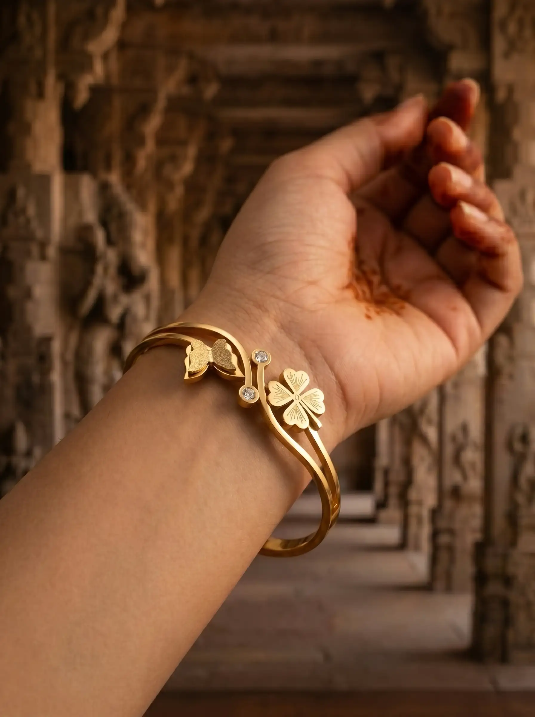 Gold plated bracelet with floral charm and butterfly detail on structured band for women