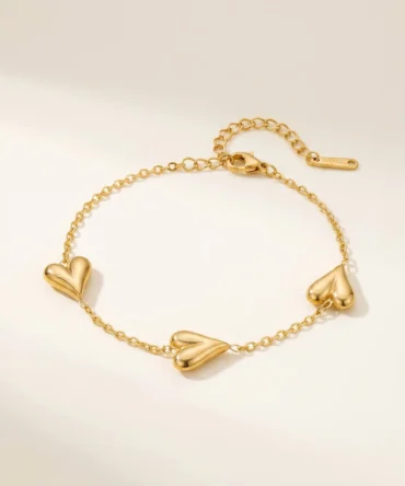 Gold tone bracelet with polished heart motifs on delicate adjustable chain for women