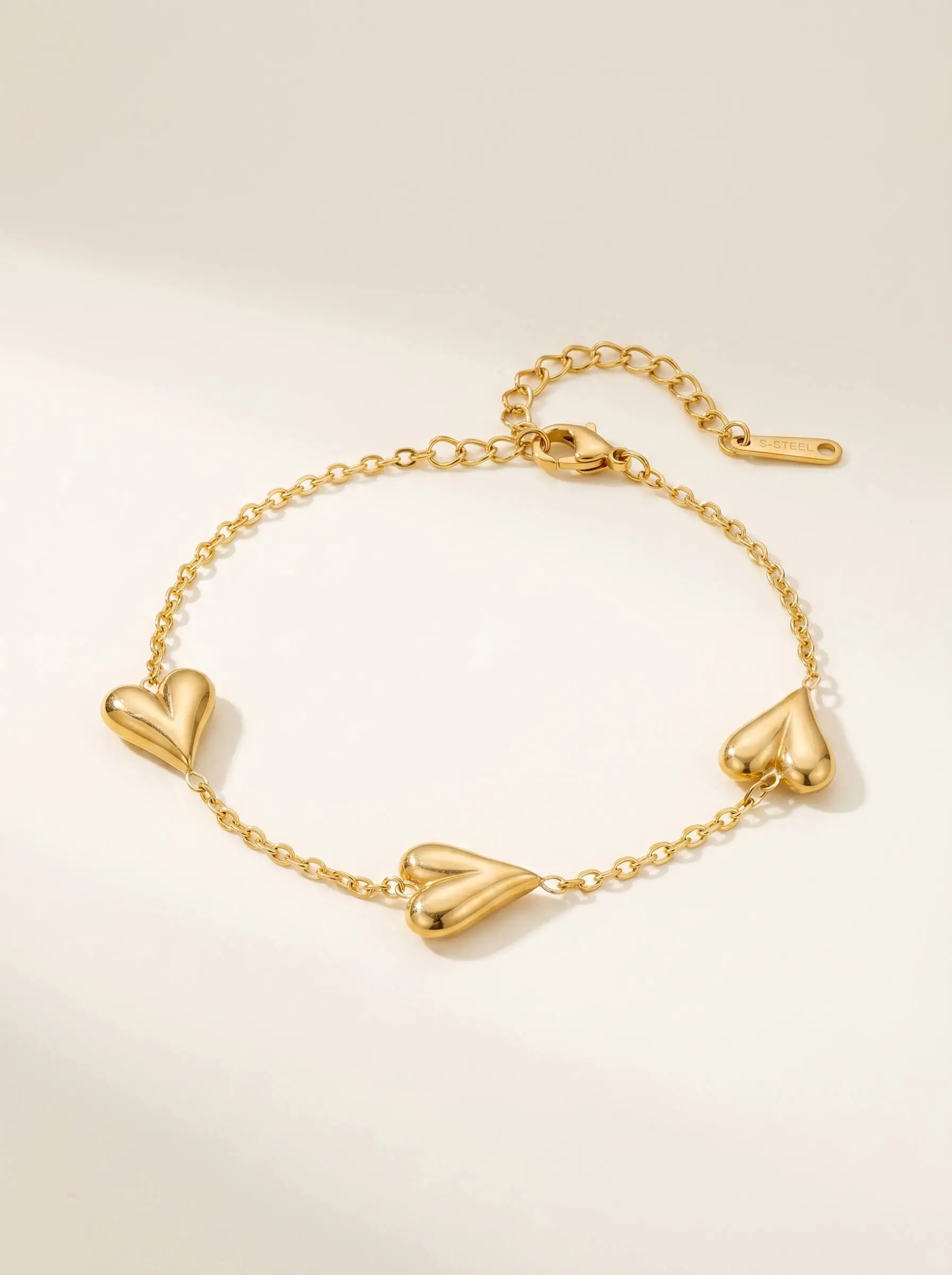 Gold tone bracelet with polished heart motifs on delicate adjustable chain for women