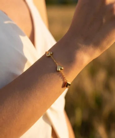 Gold tone bracelet with polished heart motifs on delicate adjustable chain for women