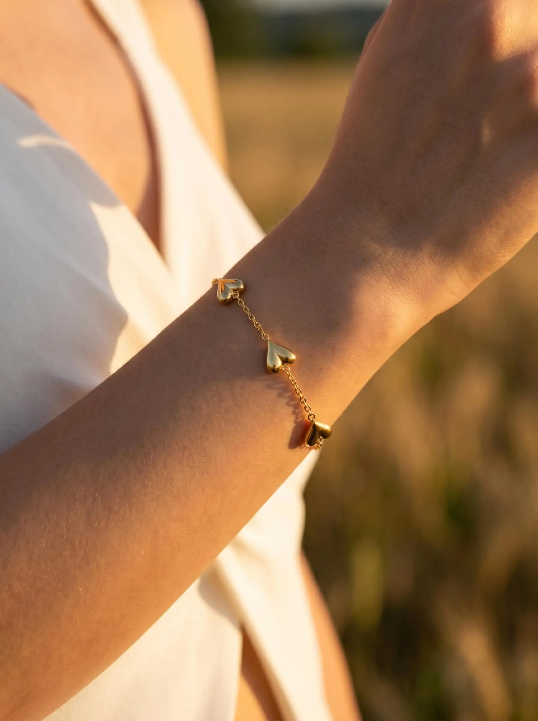 Gold tone bracelet with polished heart motifs on delicate adjustable chain for women