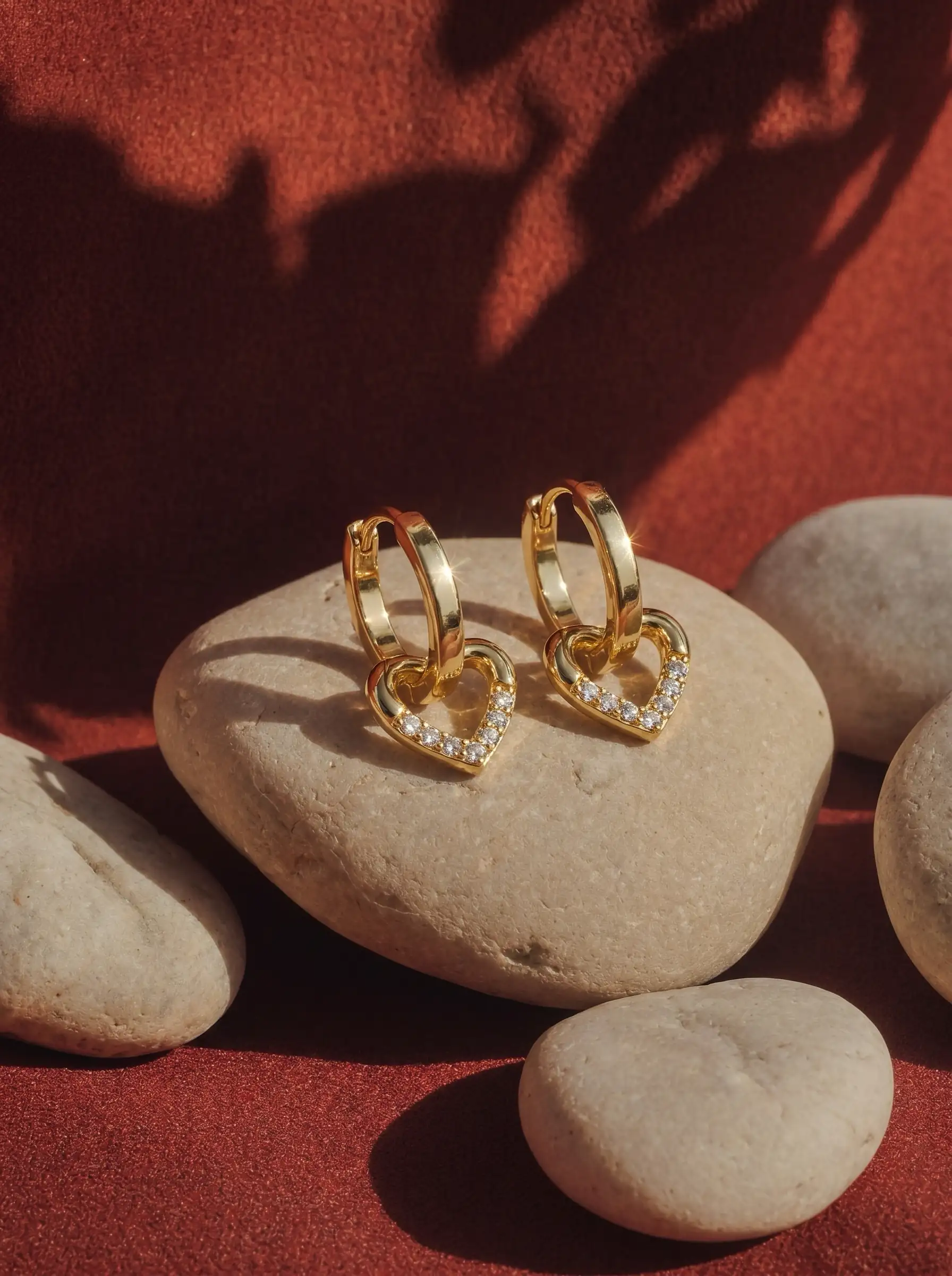 Close-up of gold plated heart drop hoop earrings with crystal detailing for women