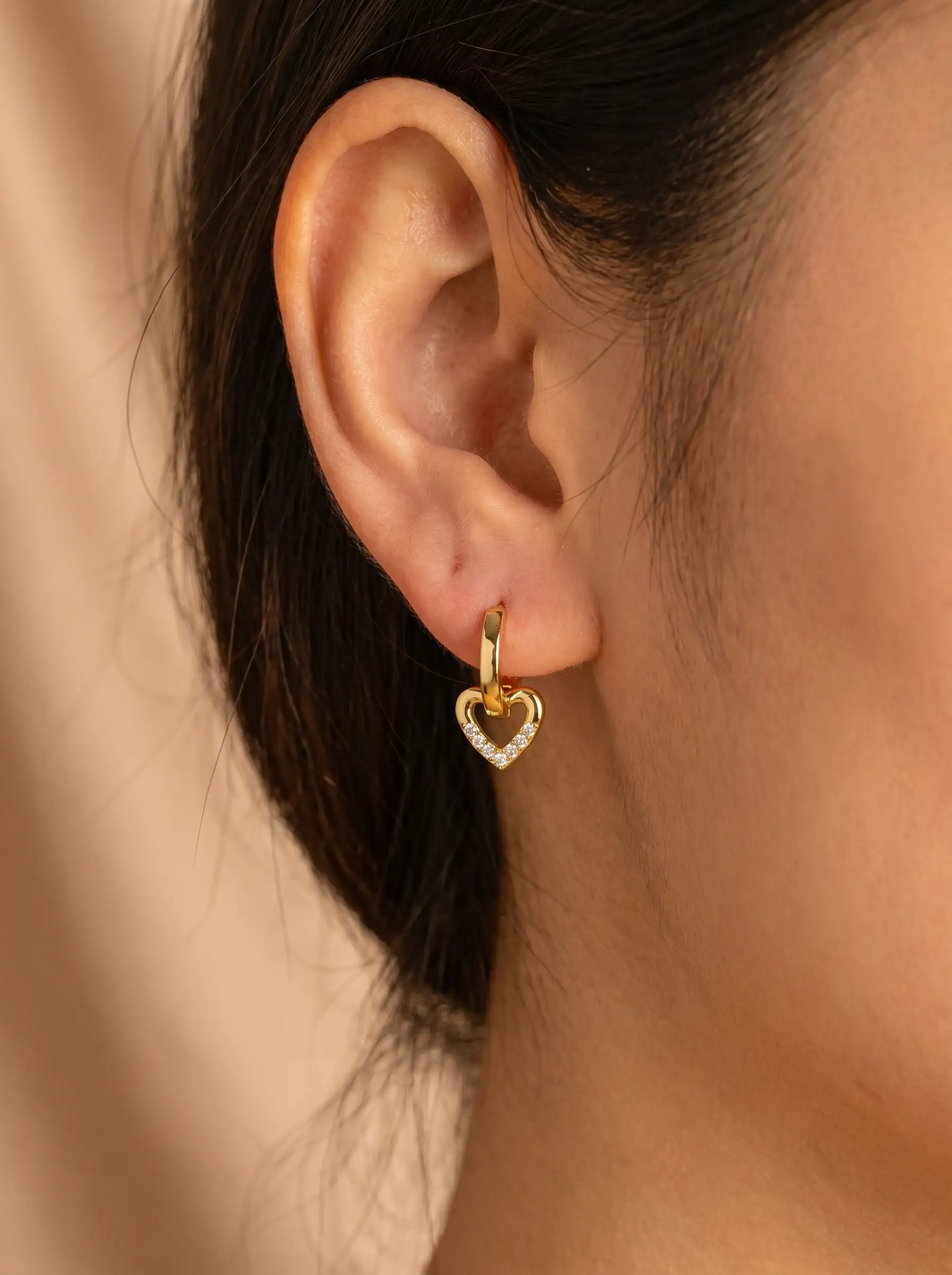 Close-up of gold plated heart drop hoop earrings with crystal detailing for women