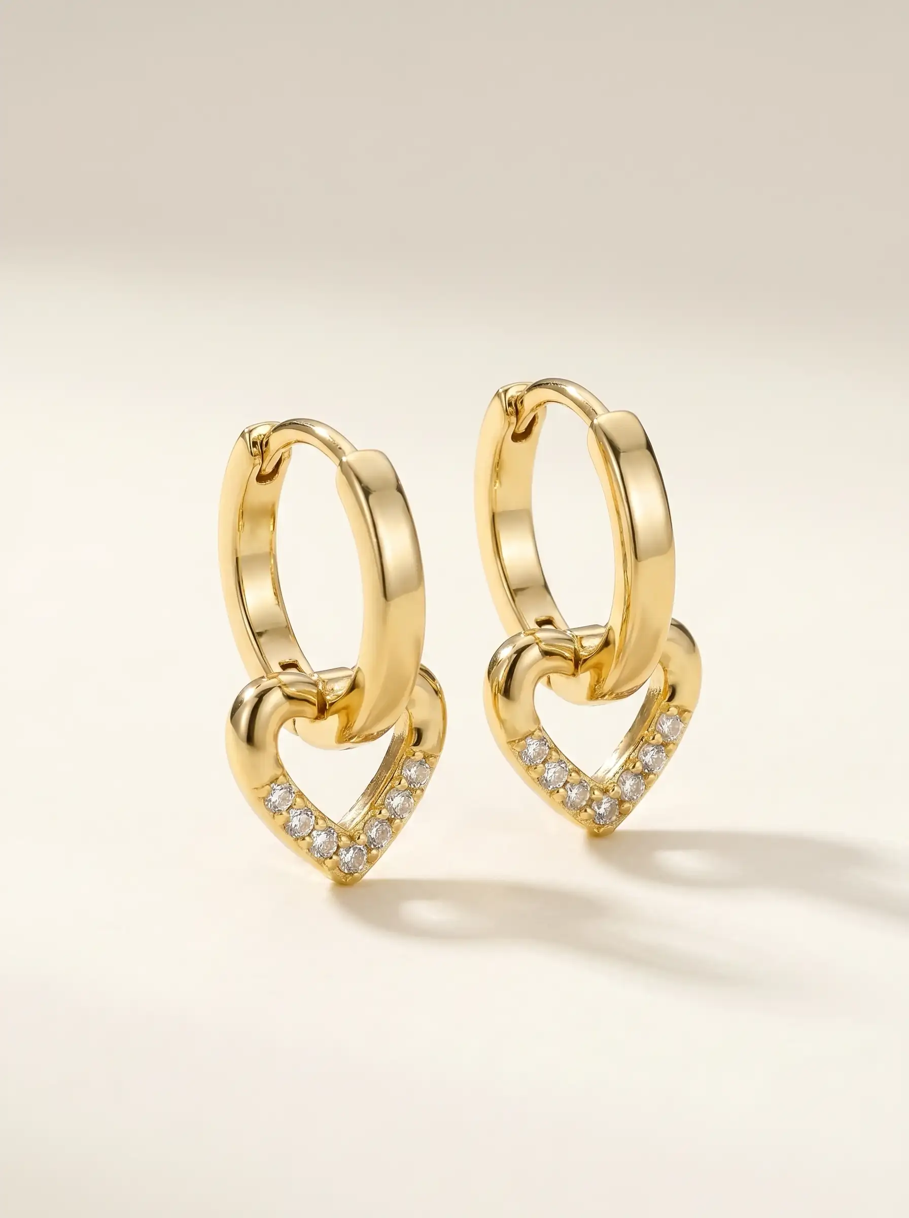 Close-up of gold plated heart drop hoop earrings with crystal detailing for women