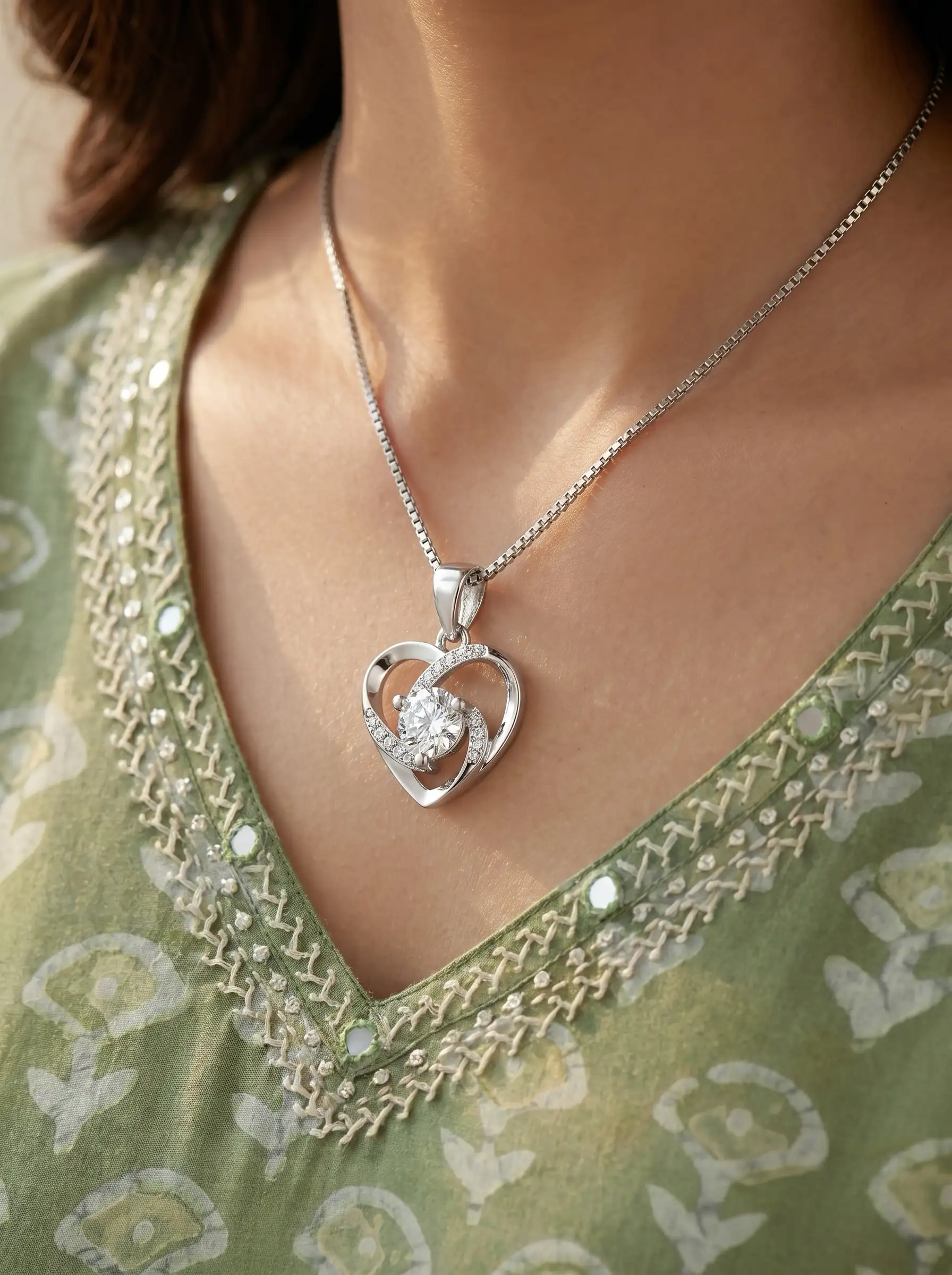 Silver tone heart shaped pendant with central crystal and curved studded detailing for women